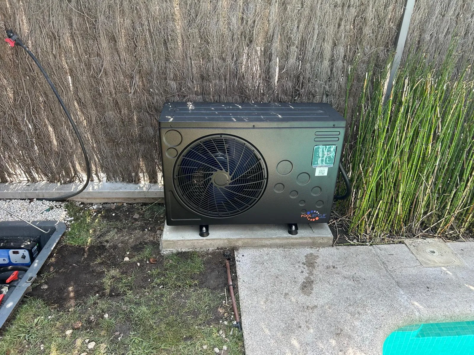 Bomba de calor instalada junto a la piscina, sobre césped