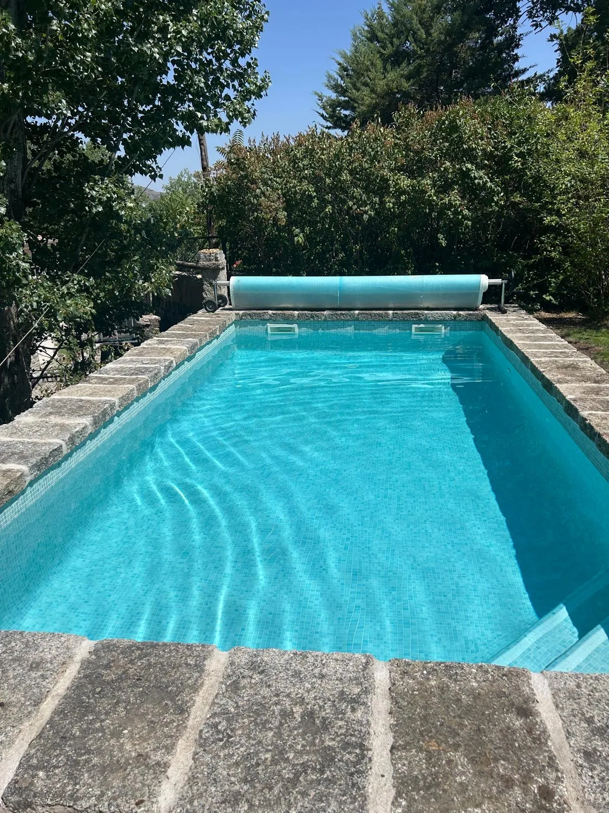 Piscina con el agua limpia y la lona enrollada en un extremo