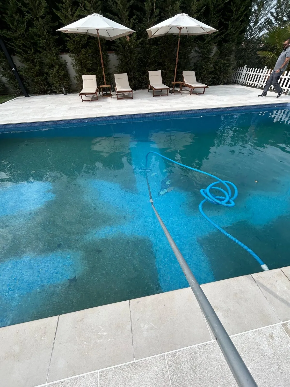 Piscina limpia con sombrillas y tumbonas