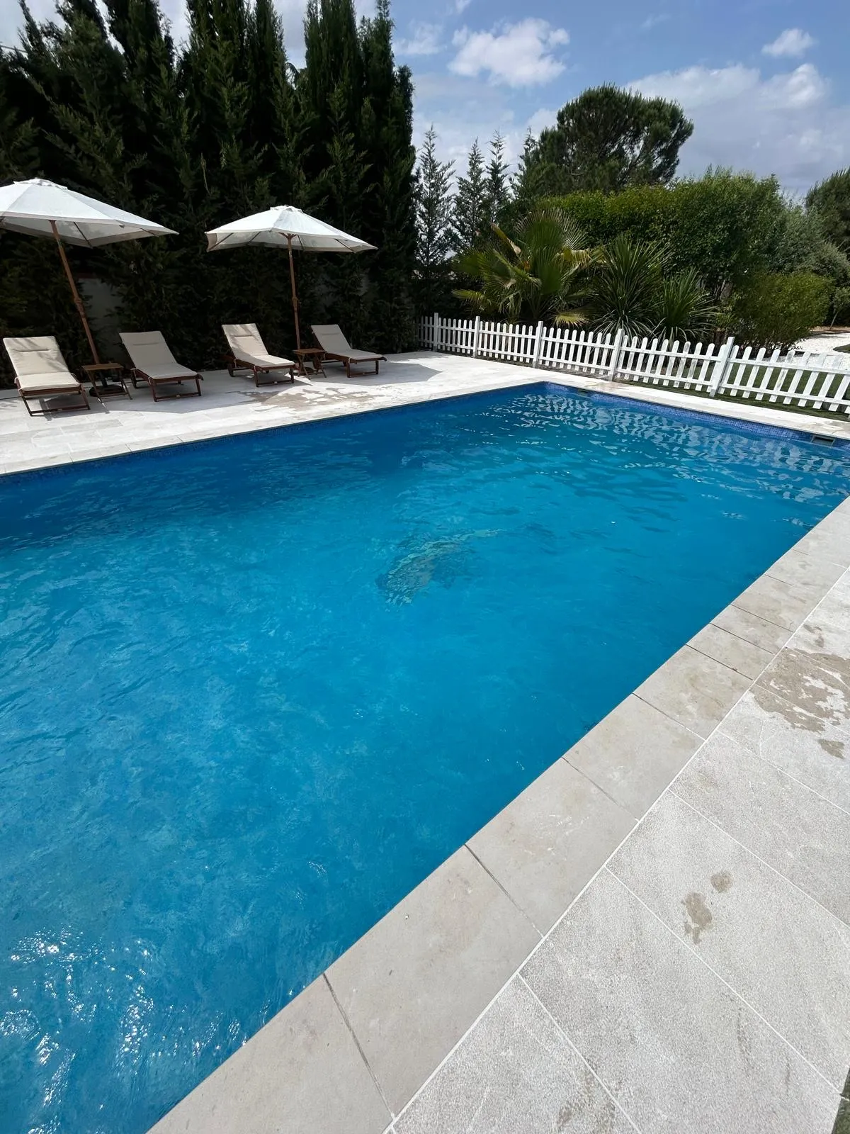 Piscina terminada y limpia, con sombrillas y tumbonas alrededor